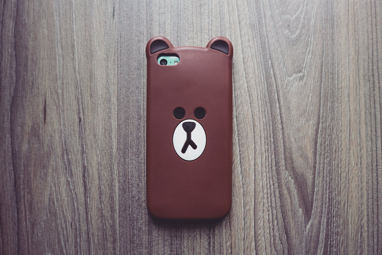 Cute bear phone case resting on a rustic wooden table, ideal for tech and lifestyle themes.